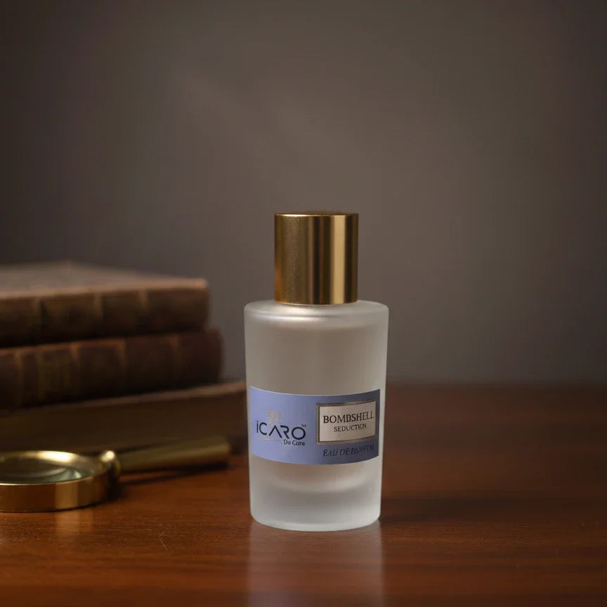 Icaro Bombshell Seduction perfume bottle with gold cap on wooden table, stacked books in background